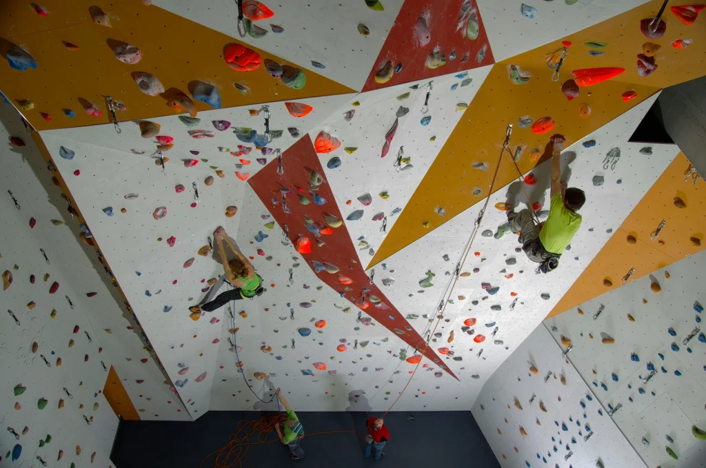 Gäste beim Indoor-Klettern an einer modernen Kletterwand – Aktivität nahe dem Apart Hotel Adelboden.