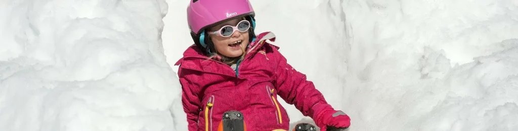 Kind mit Helm und Skibrille beim Spielen im Schnee in Adelboden