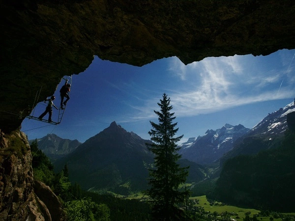 Kletterer an einer steilen Felswand mit beeindruckender Berglandschaft im Hintergrund