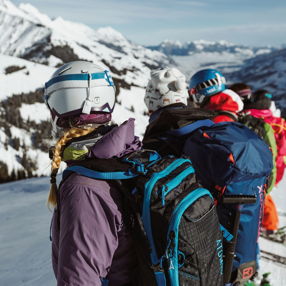 Skifahrer mit Helm und Rucksack genießen den Ausblick auf schneebedeckte Berge in Adelboden