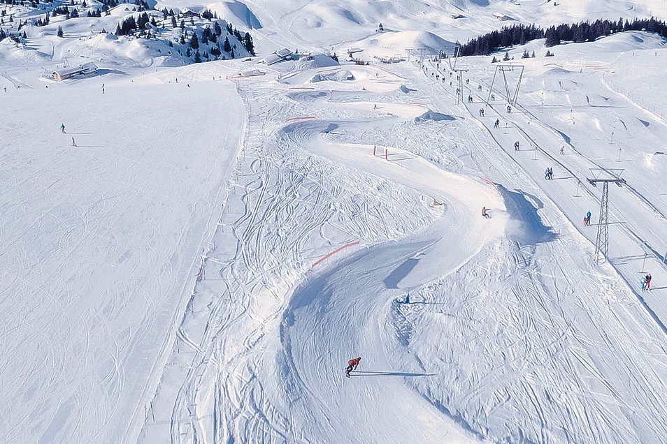 Skipiste mit Skifahrern und Sessellift in Adelboden nahe Apart Hotel bei sonnigem Wetter